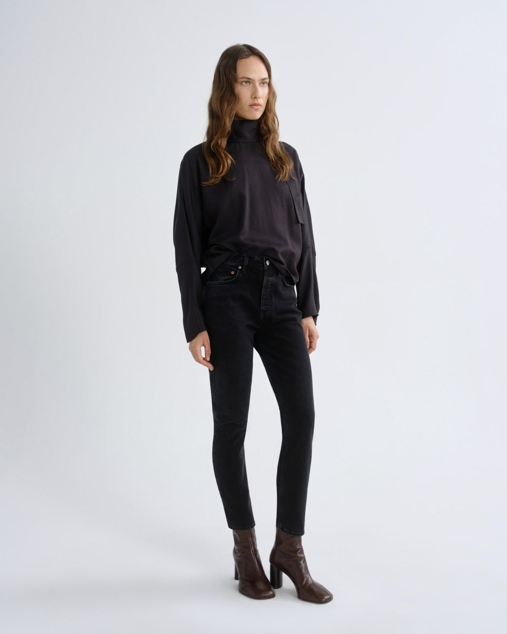 Woman wearing a black turtleneck and black pants on a white background