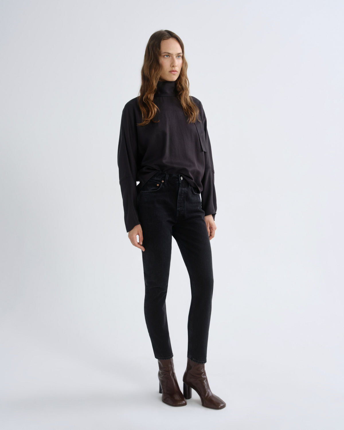 Woman wearing a black turtleneck and black pants on a white background