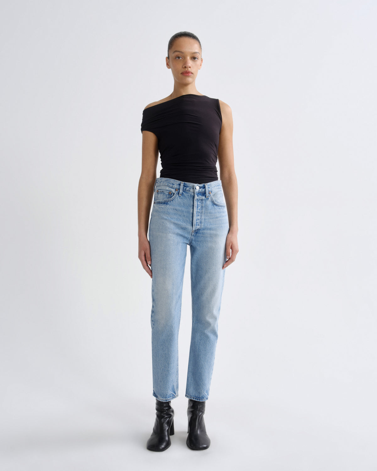 Person wearing a black top and light blue jeans on a white background