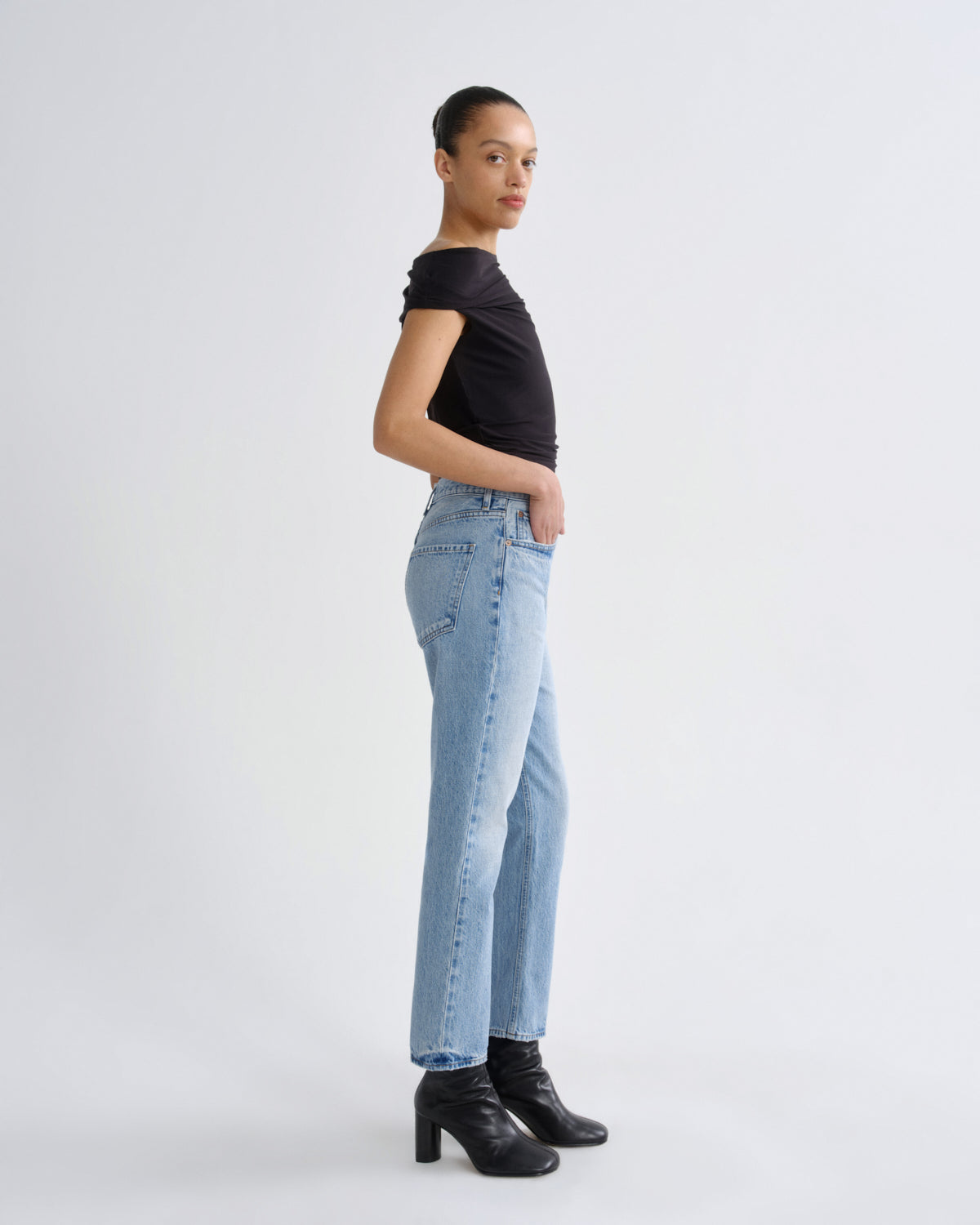 Person wearing a black t-shirt and light blue jeans on a white background