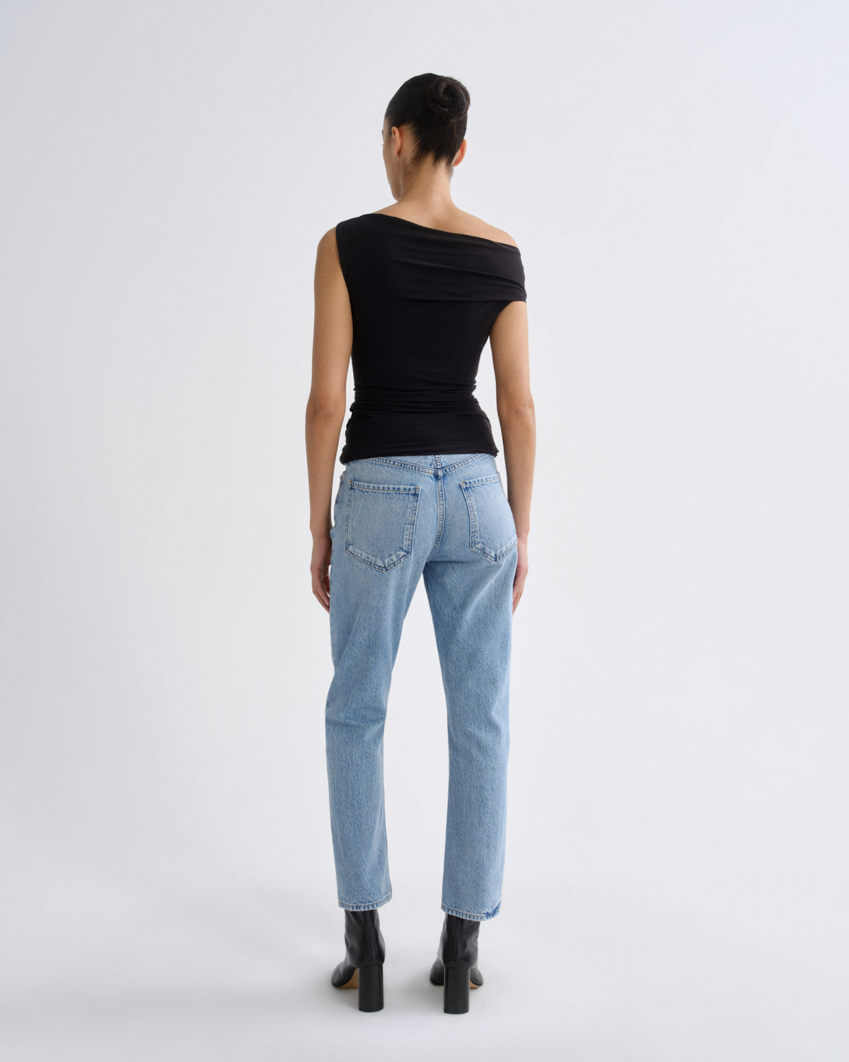 Person wearing light blue jeans and a black top on a white background