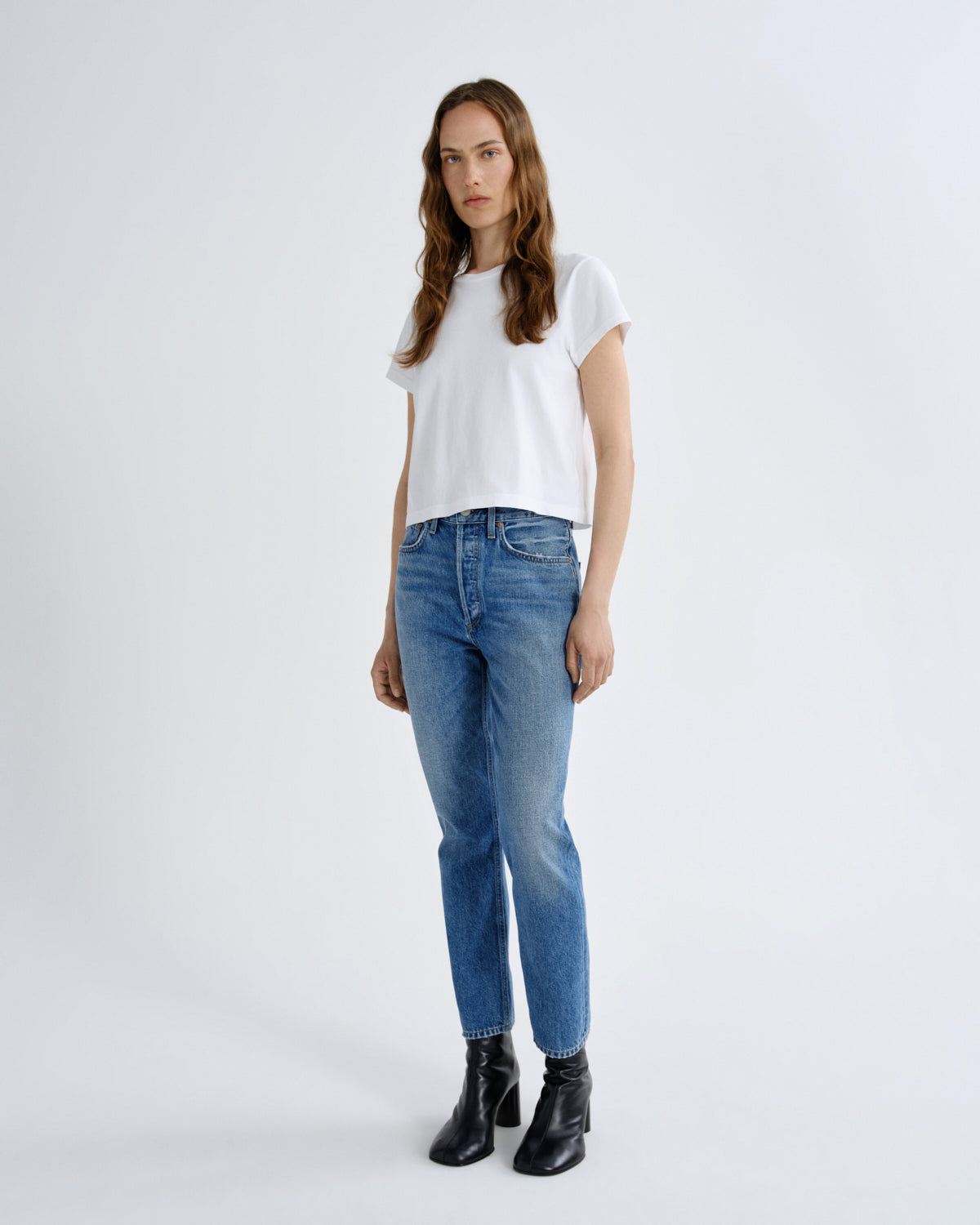 Woman wearing a white t-shirt and blue jeans on a white background