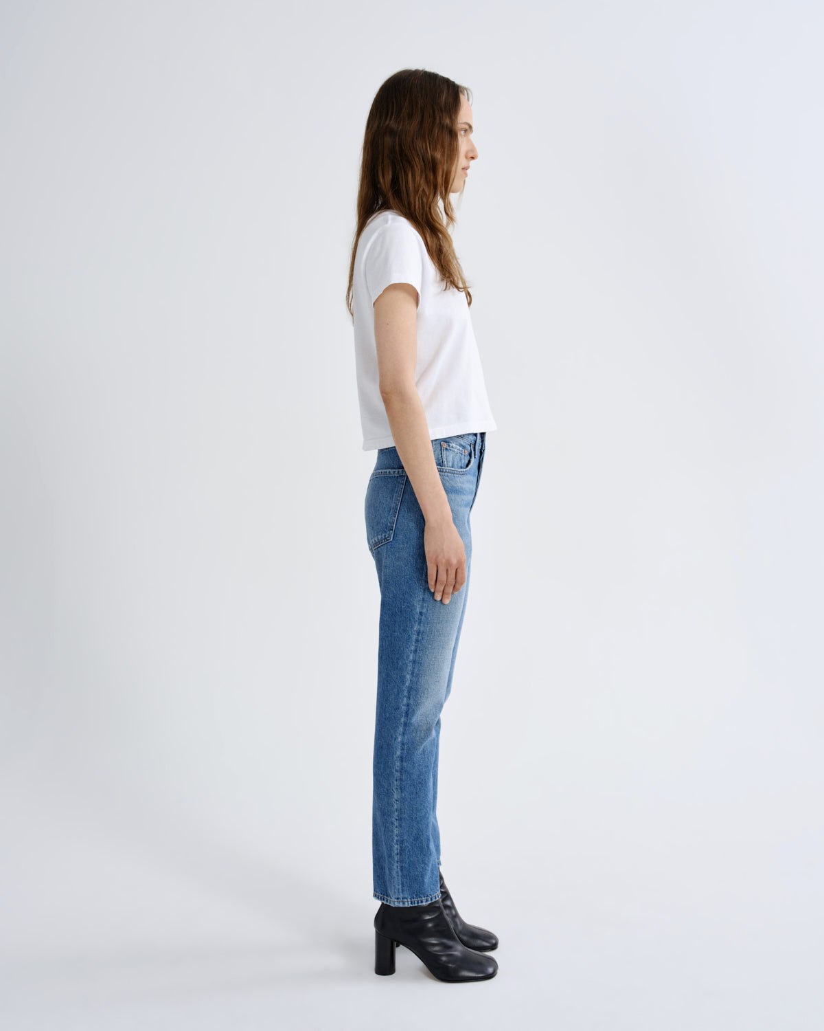 Woman wearing a white t-shirt and blue jeans on a white background