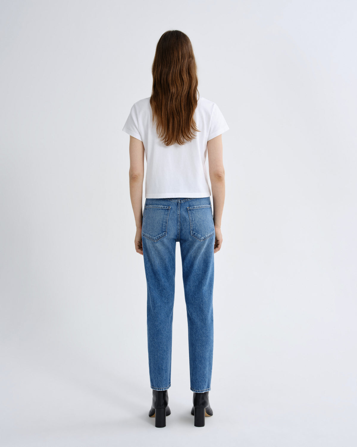Person wearing blue jeans and a white t-shirt on a white background