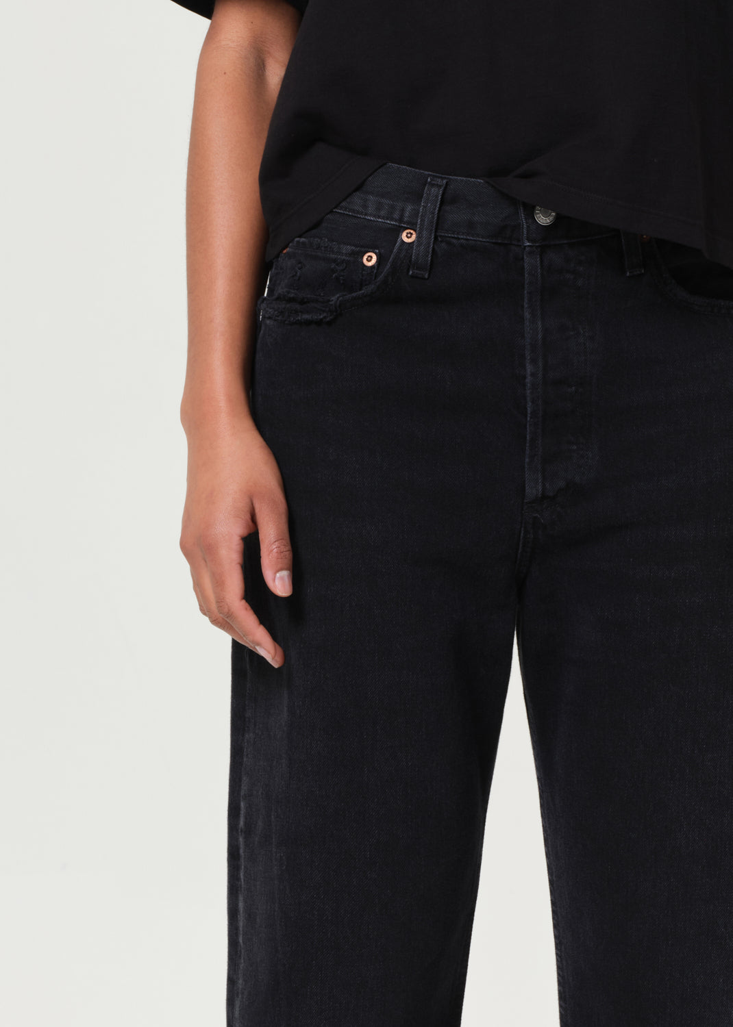 Person wearing black jeans with a plain background