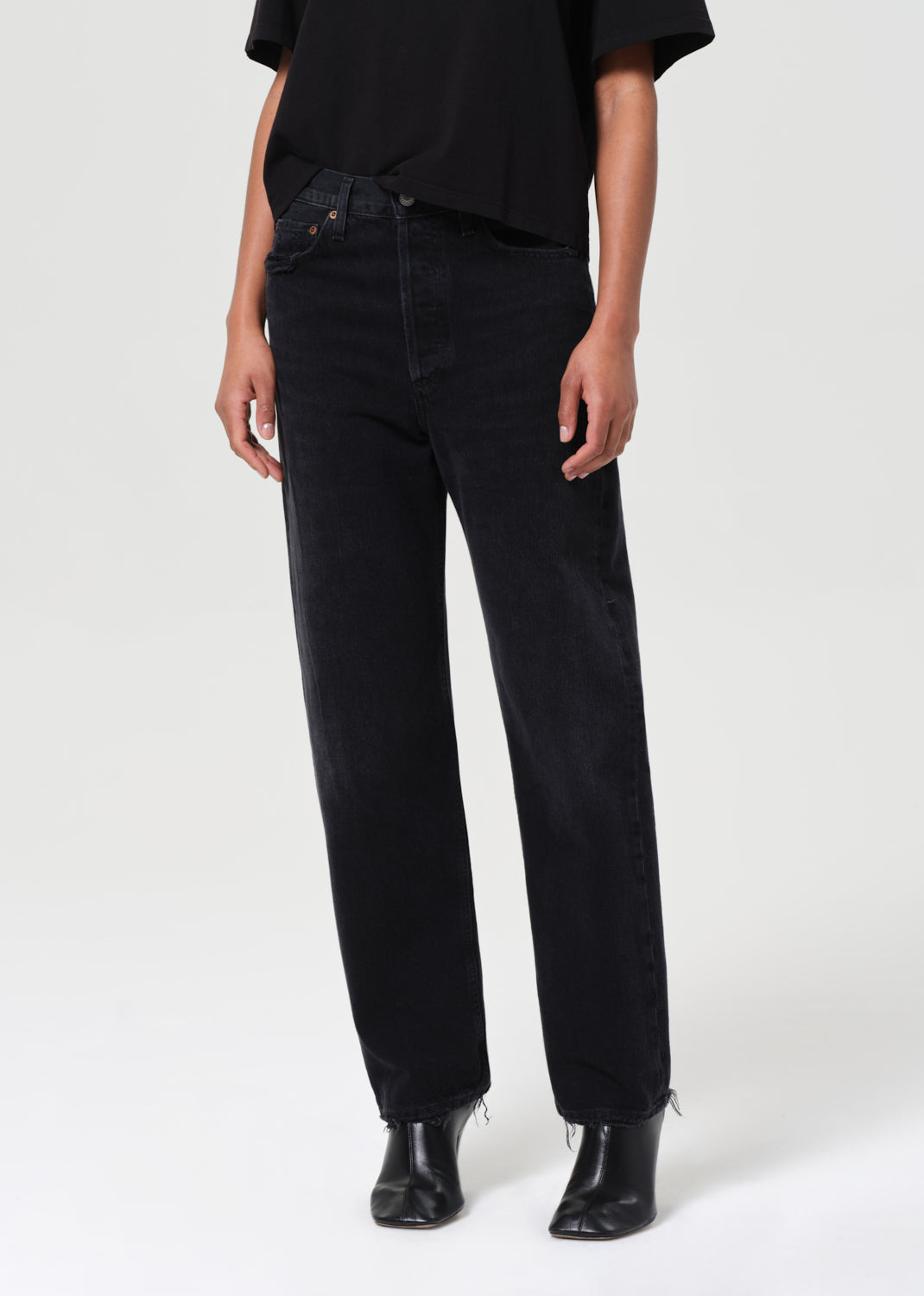 Person wearing black jeans and black shoes on a white background