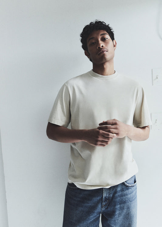 Man wearing a plain white t-shirt and blue jeans against a white background