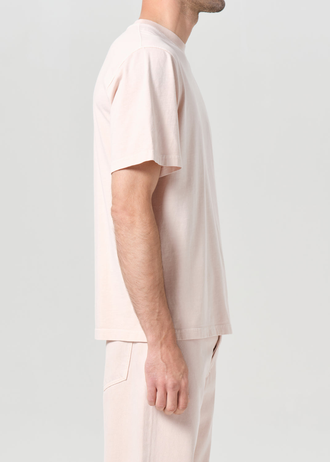 Person wearing a light pink t-shirt and pants on a white background