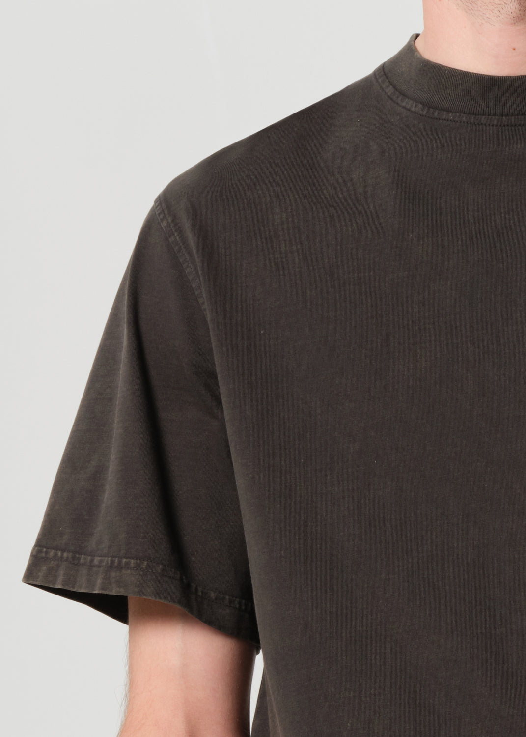 Dark gray t-shirt worn by a person on a light gray background