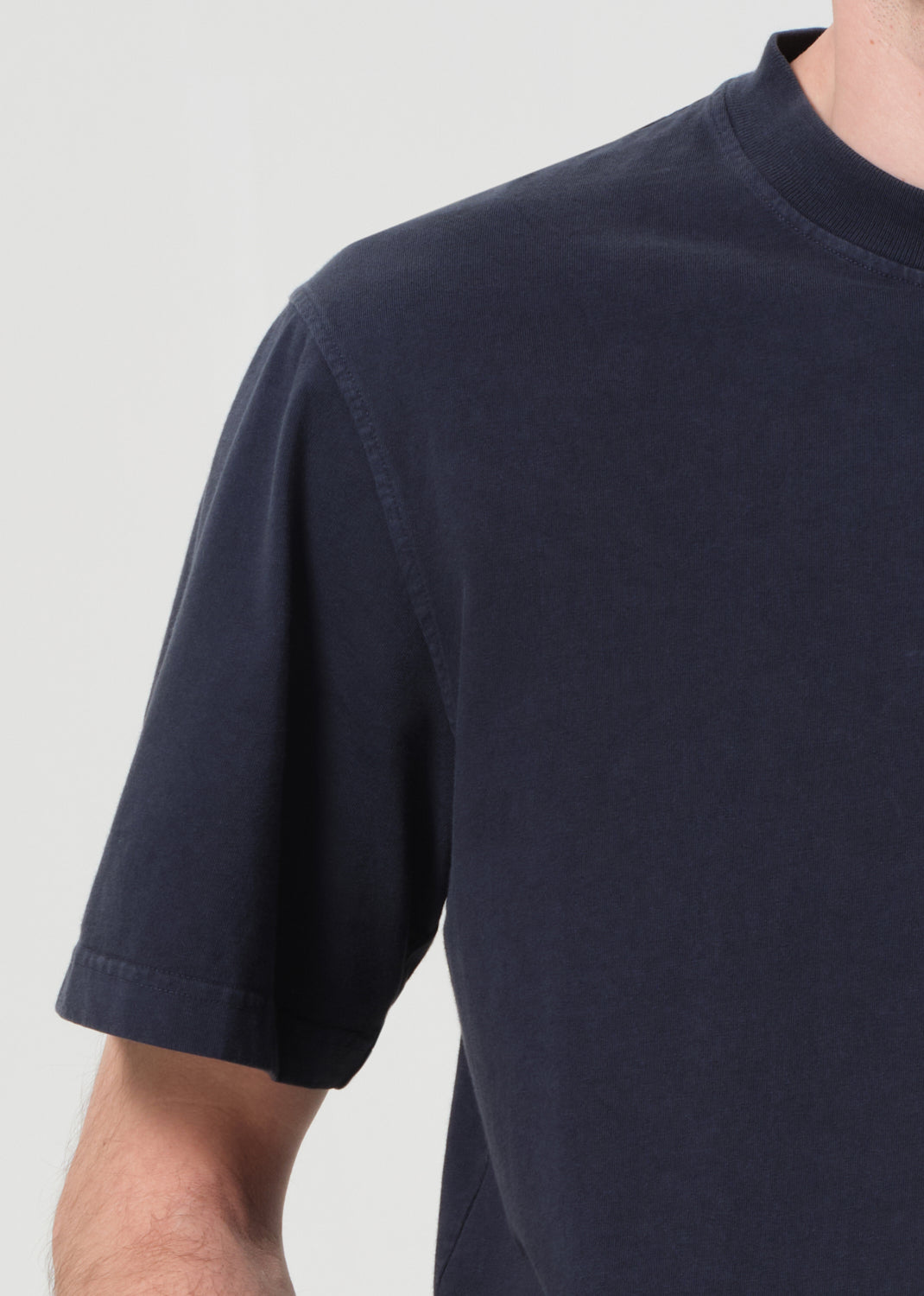 Navy blue t-shirt worn by a person on a light gray background
