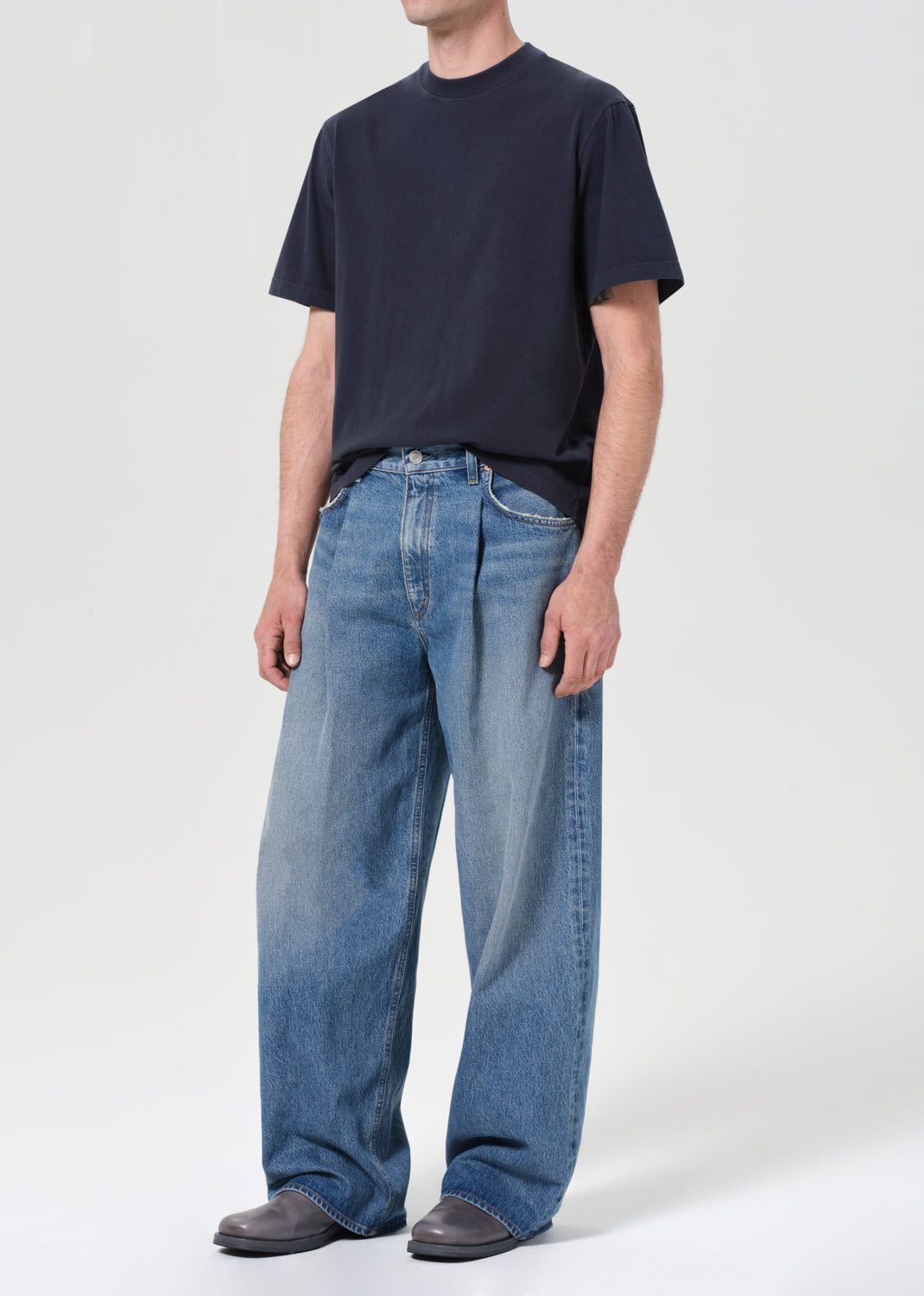 Person wearing a navy t-shirt and blue jeans on a white background