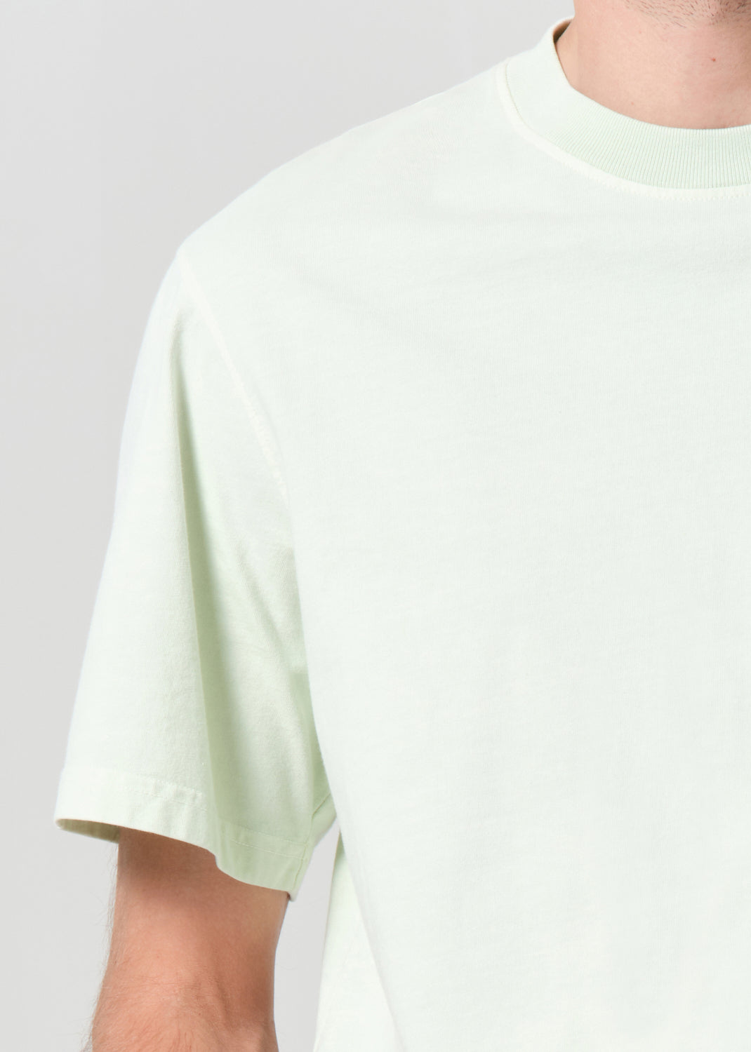 Light green t-shirt worn by a person on a plain background