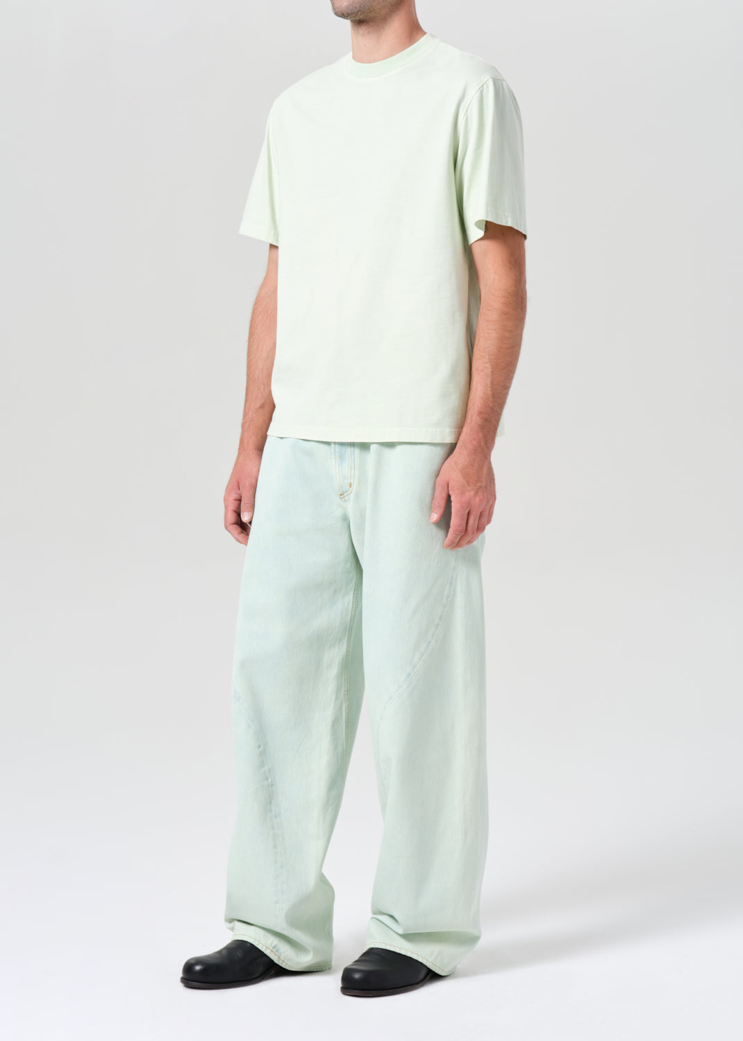 Person wearing a light green t-shirt and wide-leg pants on a white background