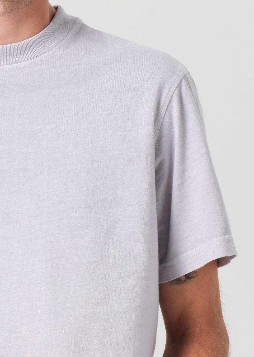 Person wearing a light gray t-shirt against a plain background