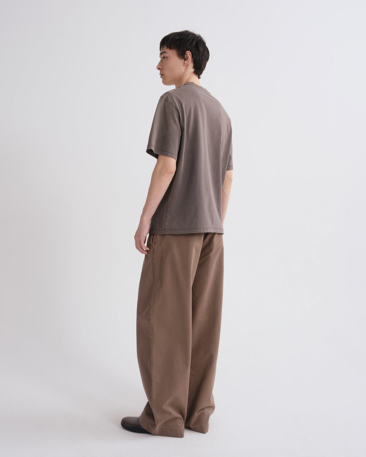 Person wearing a brown t-shirt and wide-leg pants on a white background