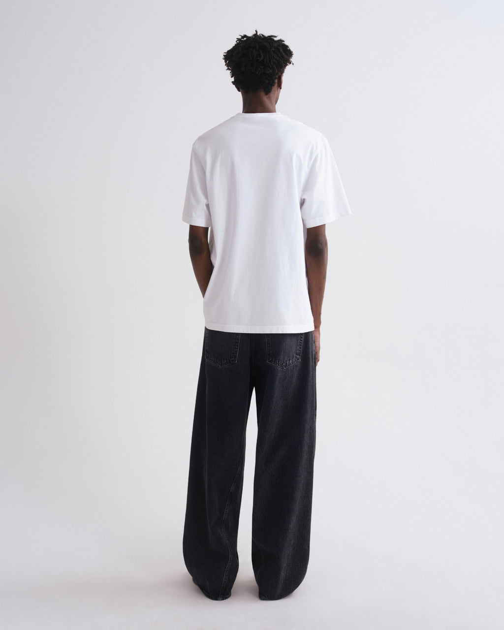 Person wearing a white t-shirt and black pants on a white background