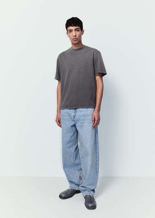 Person wearing a gray t-shirt and light blue jeans on a white background