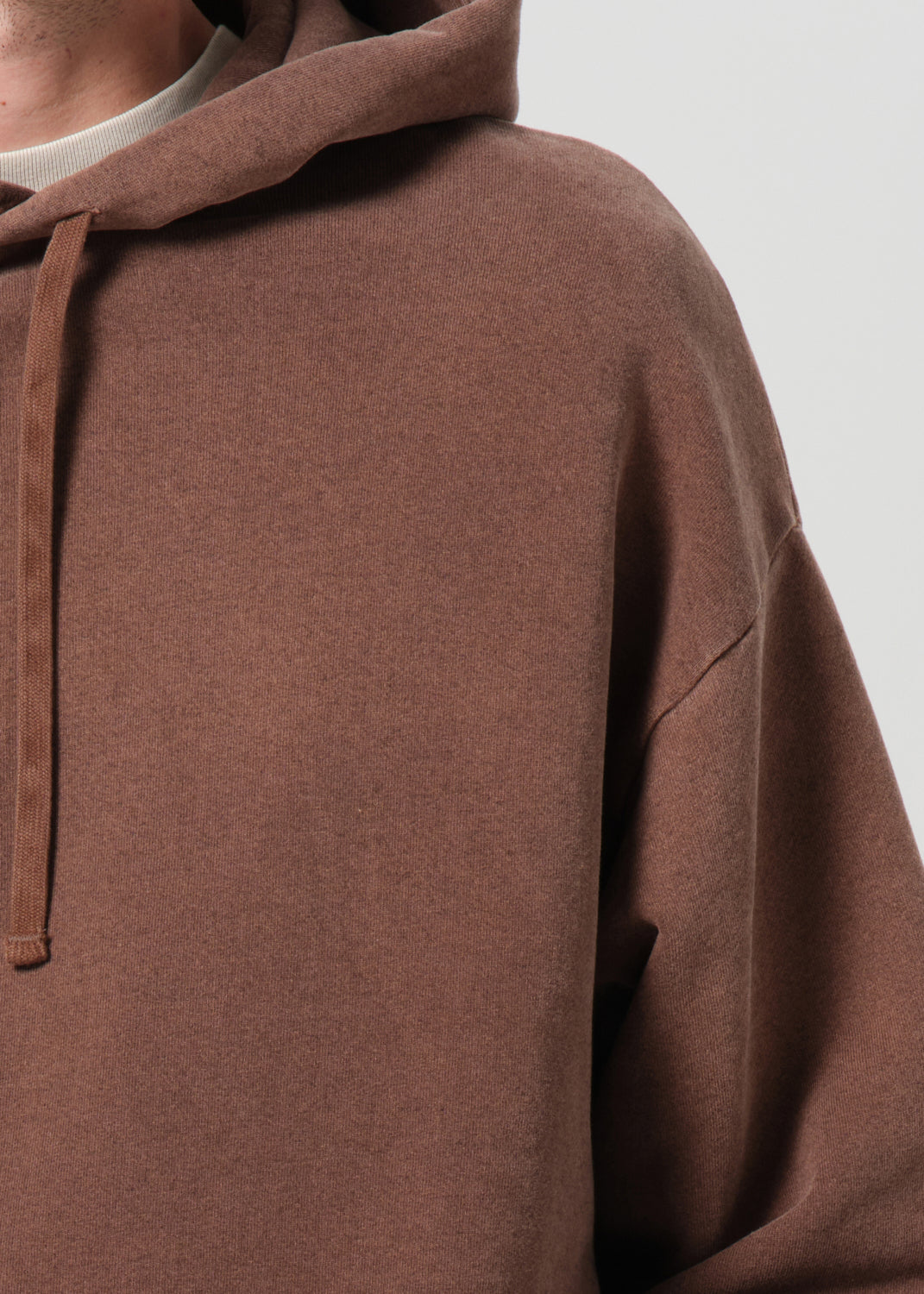 Brown hoodie worn by a person on a light gray background