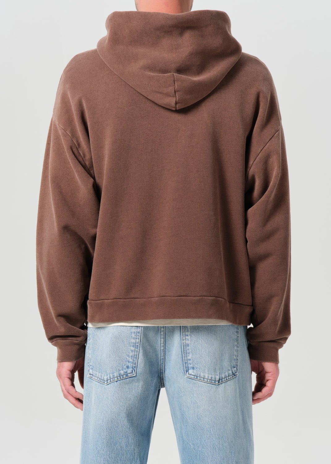 Brown hoodie worn by a person on a plain background