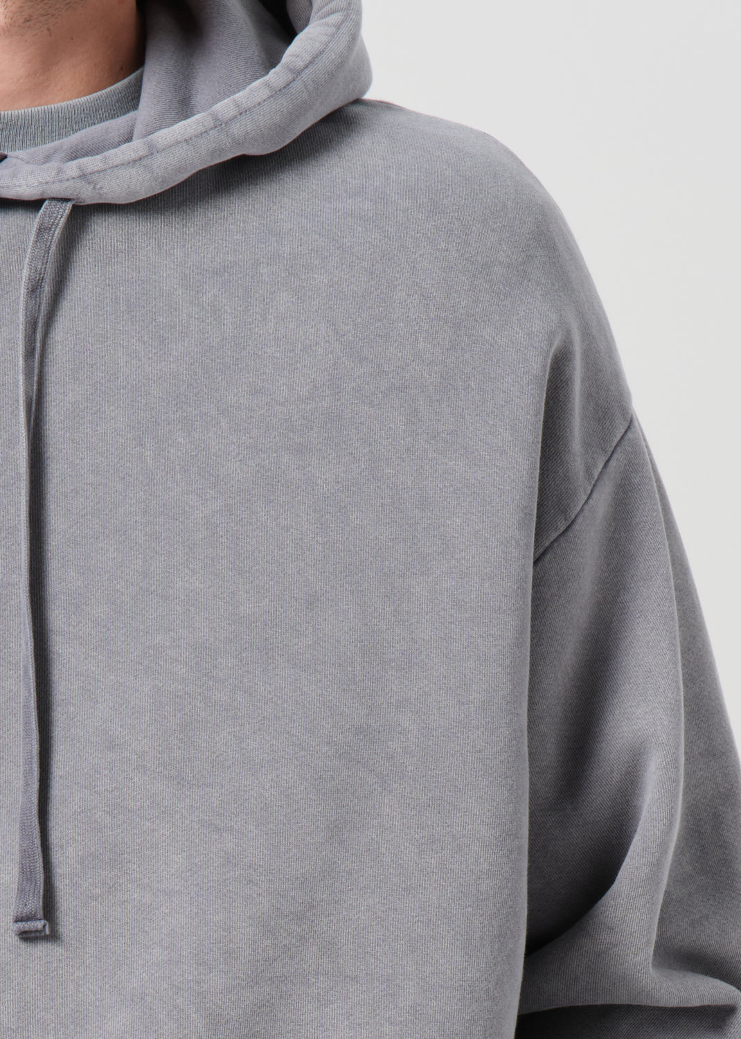 Gray hoodie with a focus on the hood and sleeve on a light gray background