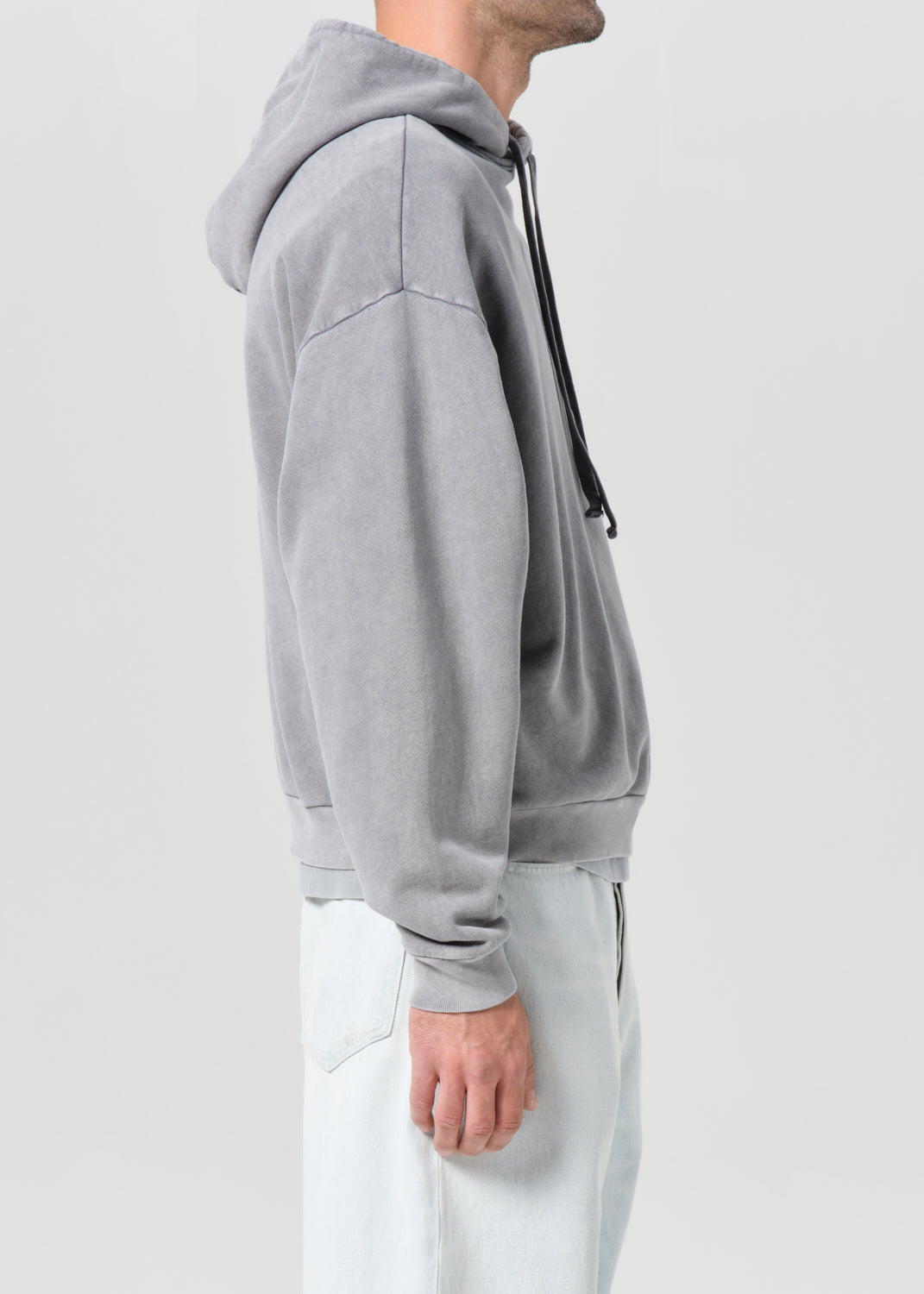 Person wearing a gray hoodie with a zipper on a light gray background