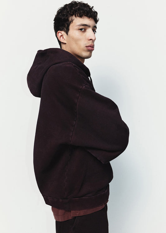 Man wearing a dark brown hoodie against a light gray background