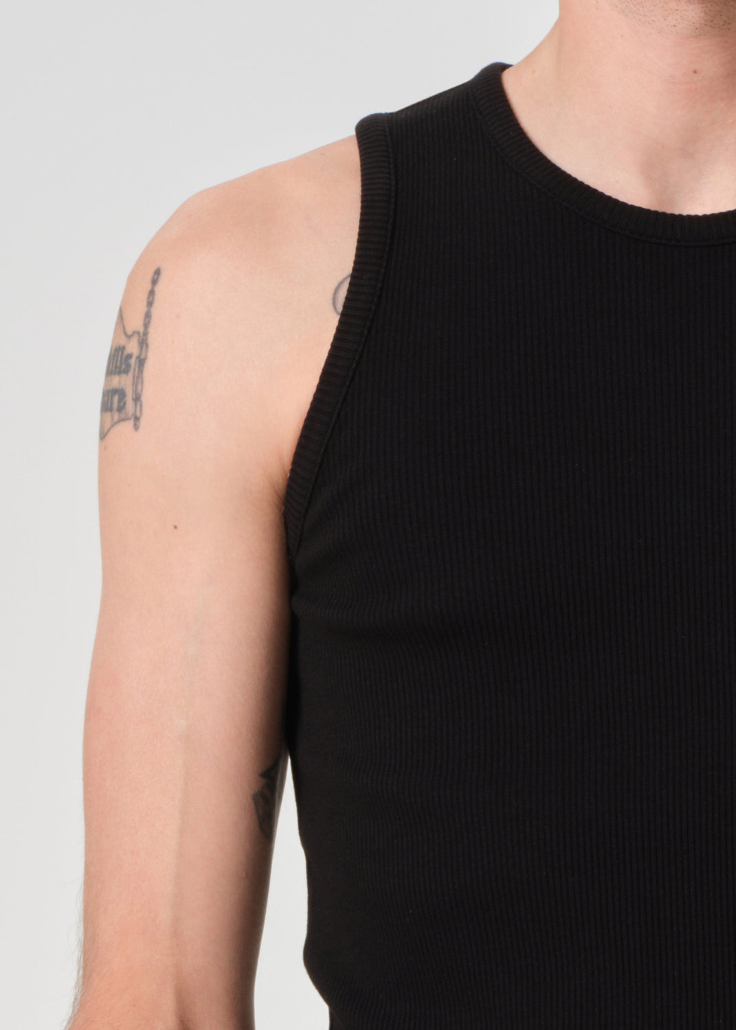 Person wearing a black tank top with a plain background