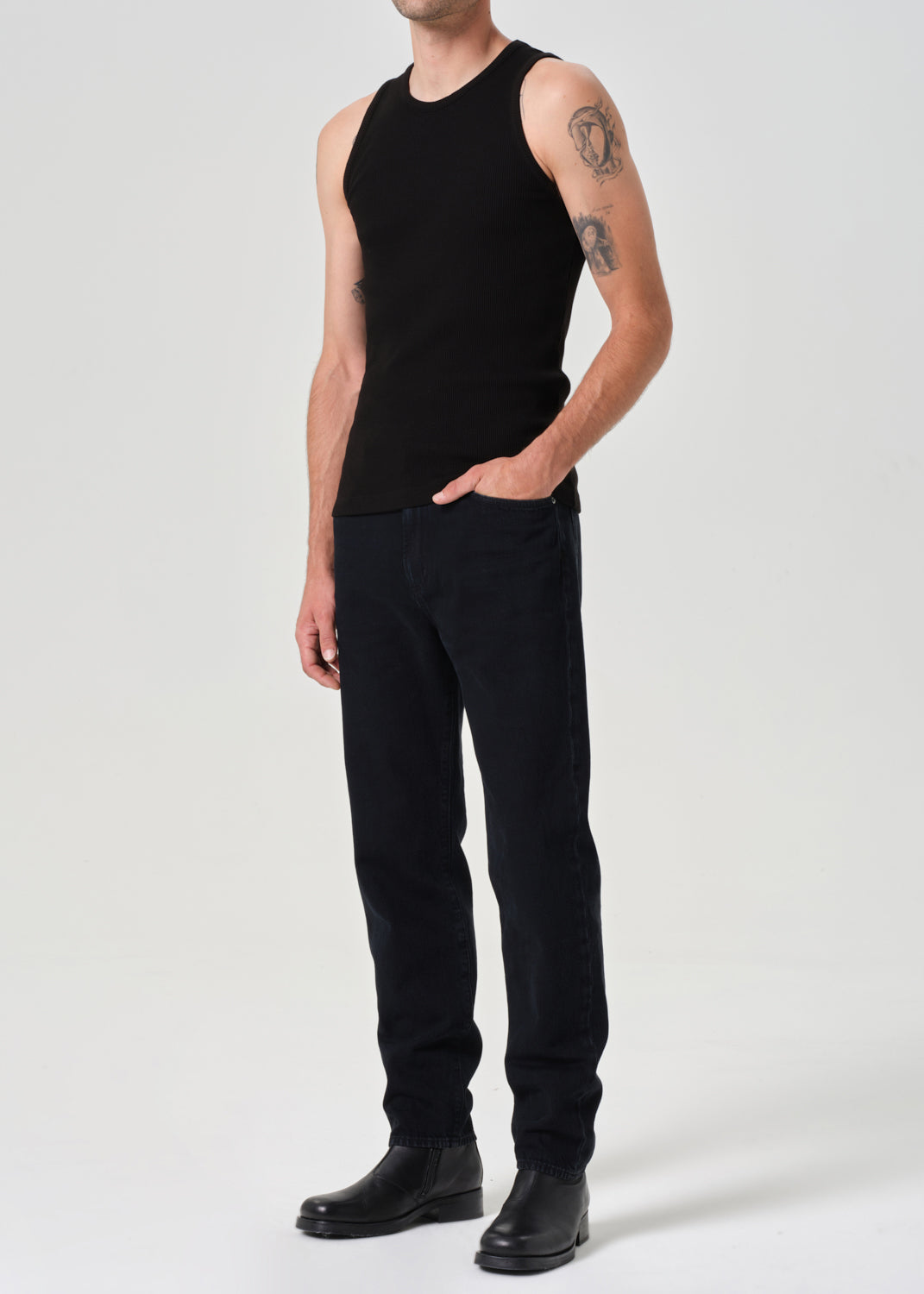 Person wearing a black sleeveless shirt and black pants on a white background
