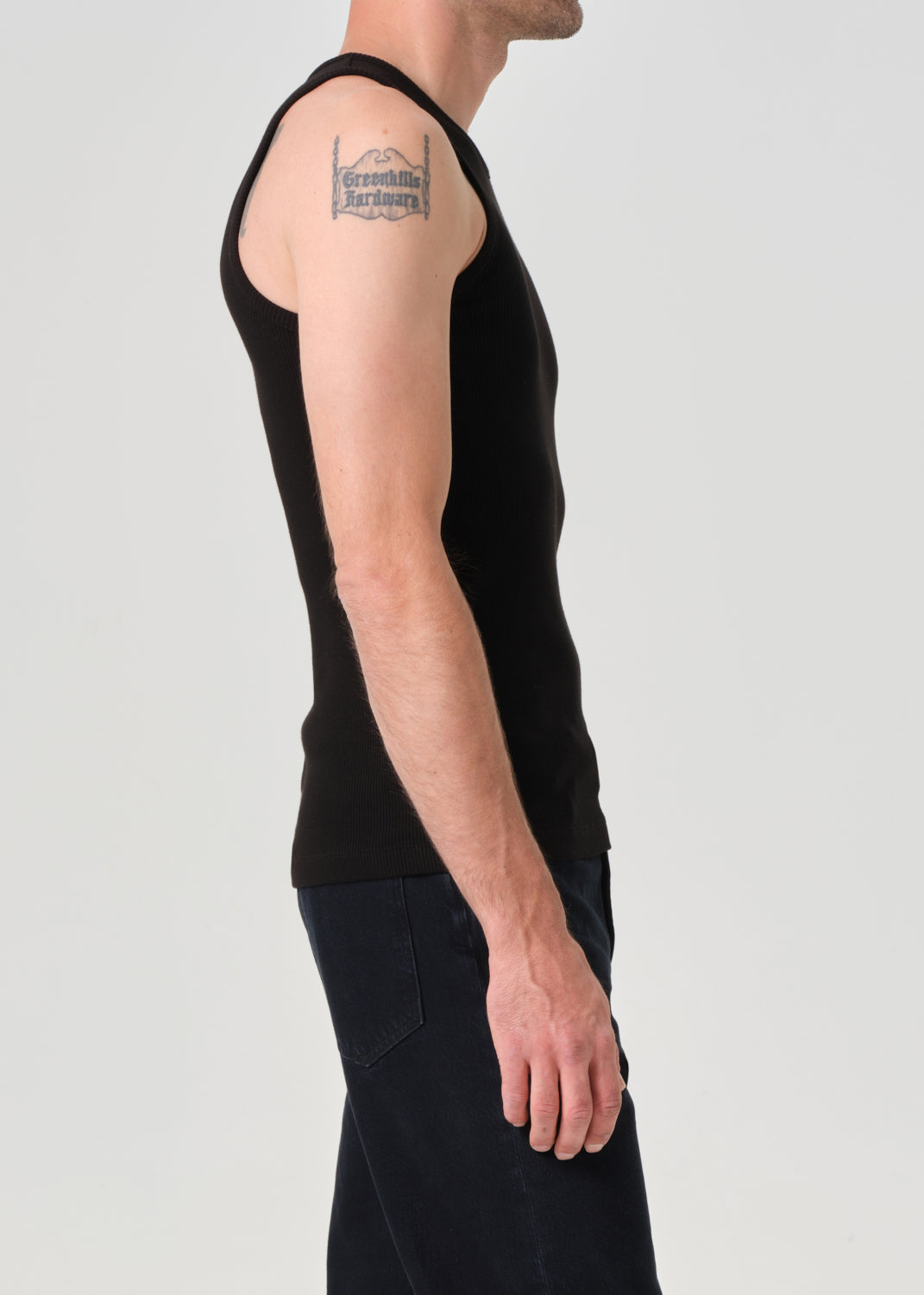 Person wearing a black sleeveless shirt against a plain background