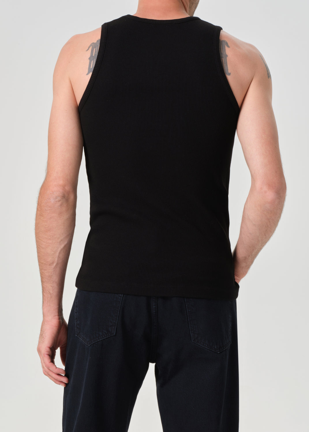 Person wearing a black sleeveless shirt and pants on a plain background
