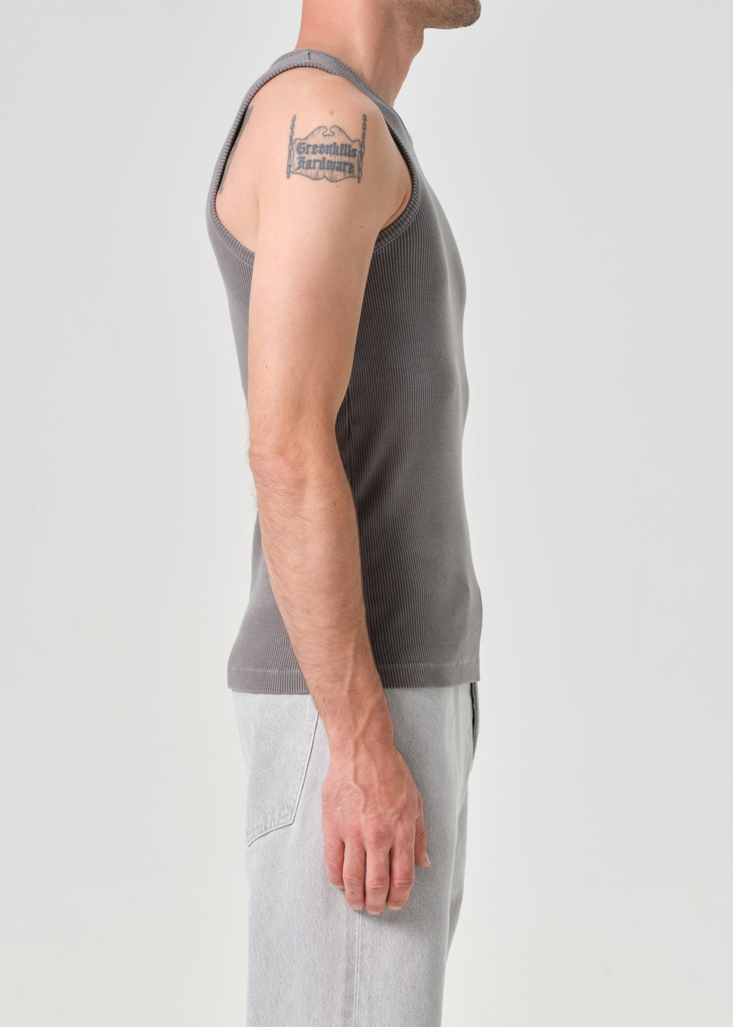 Person wearing a grey sleeveless shirt on a grey background