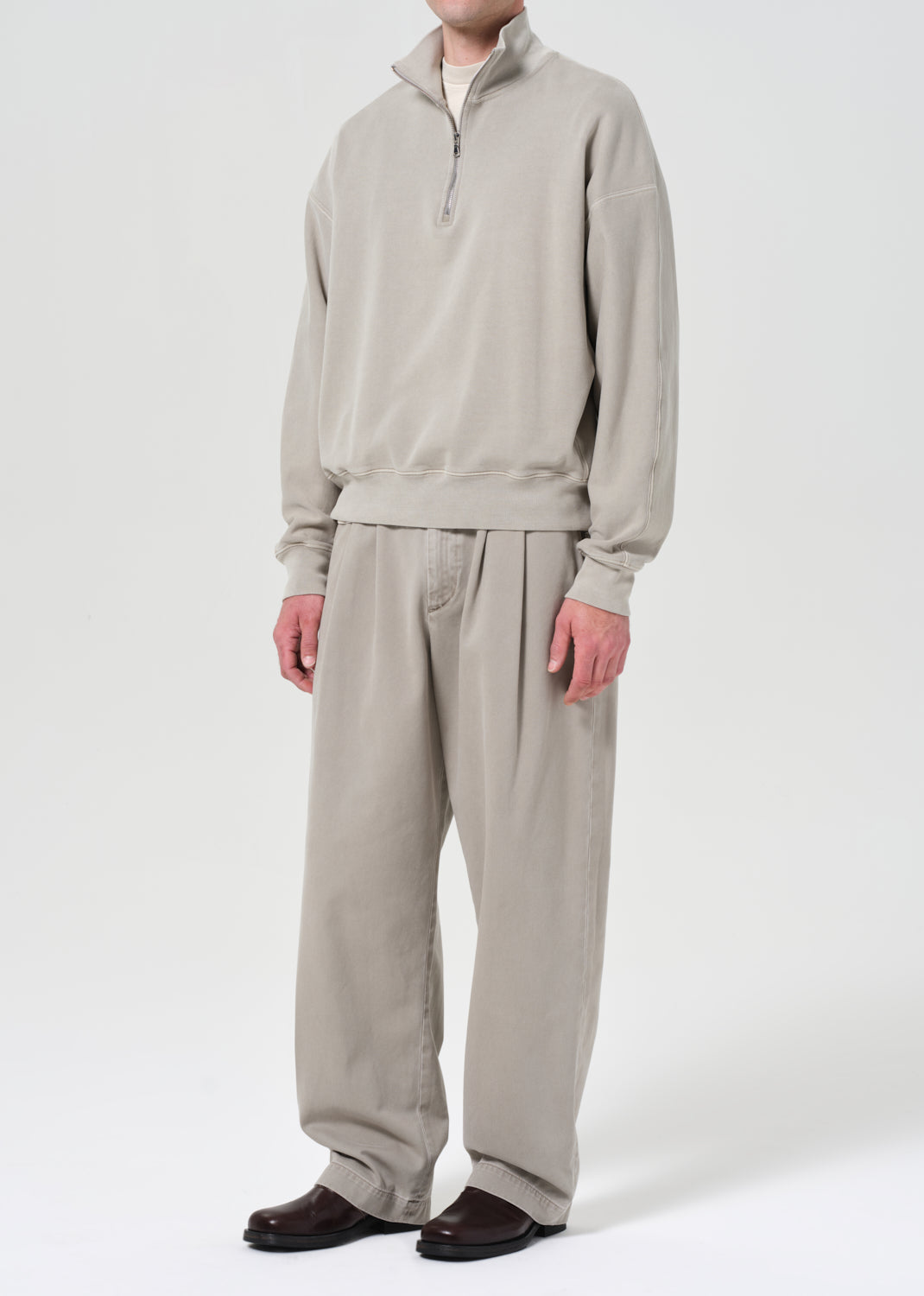 Person wearing a beige tracksuit on a white background