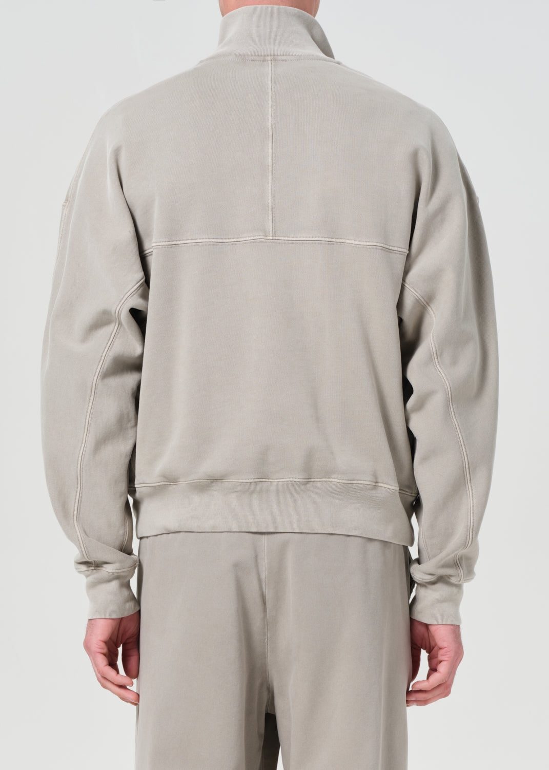 Beige tracksuit worn by a person on a white background