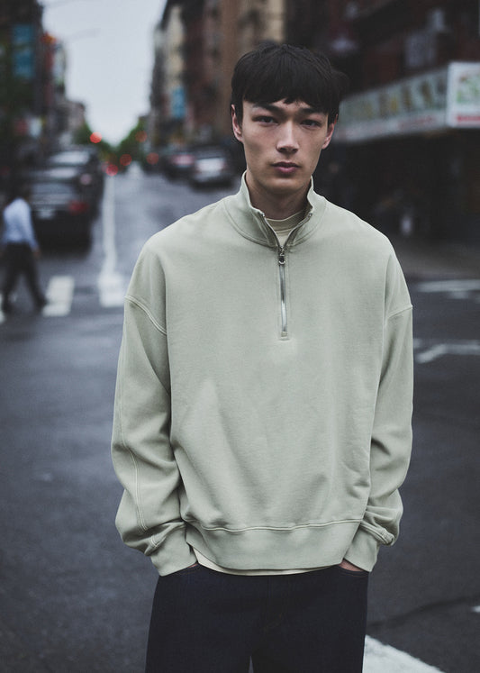 Man wearing a light green sweatshirt on a city street