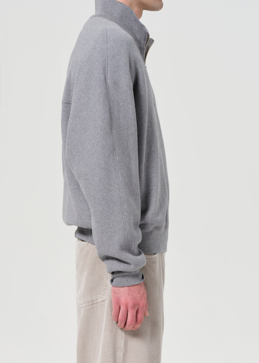 Person wearing a gray fleece jacket on a plain background