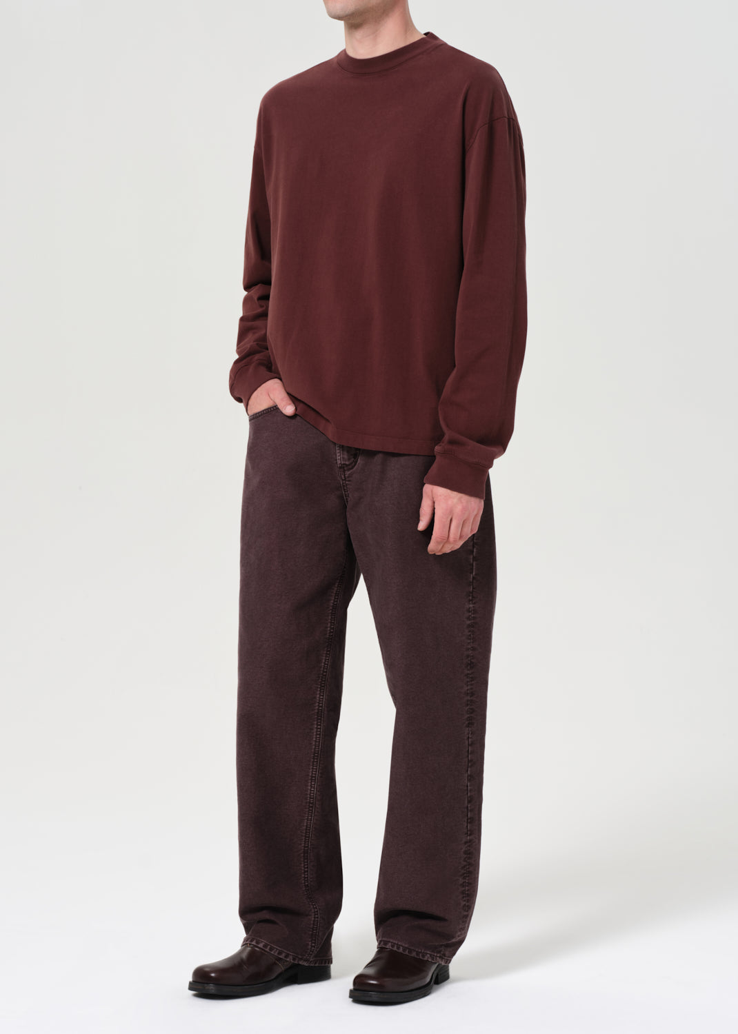 Person wearing a brown sweater and pants on a white background