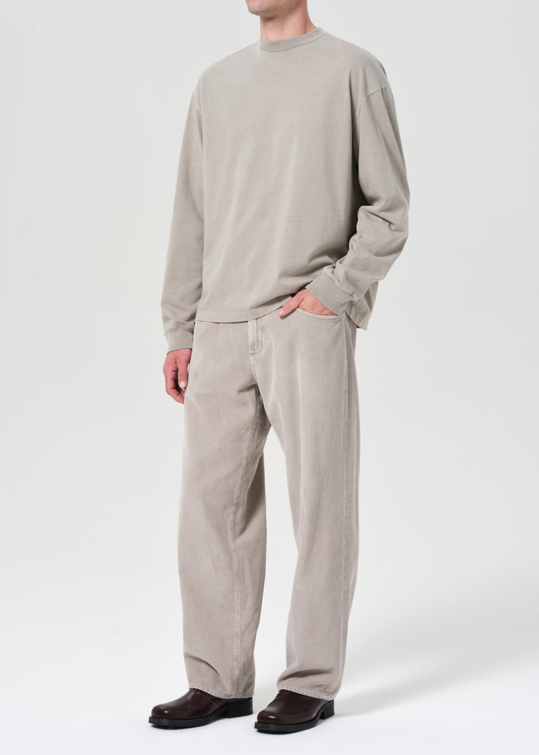 Person wearing a beige sweater and pants on a white background