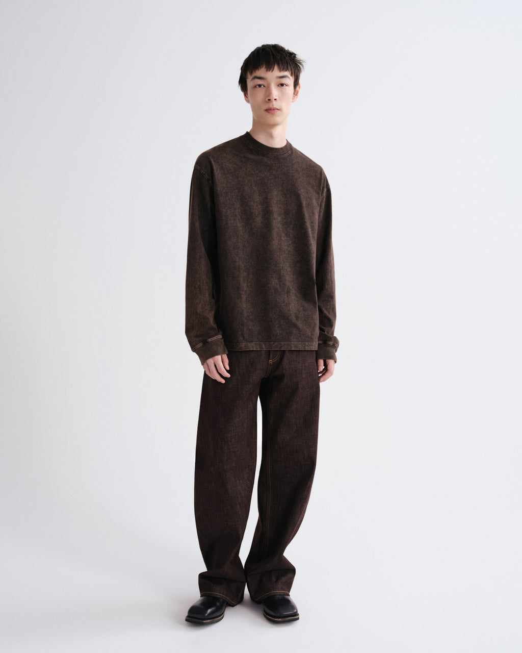 Person wearing a brown sweater and pants on a white background