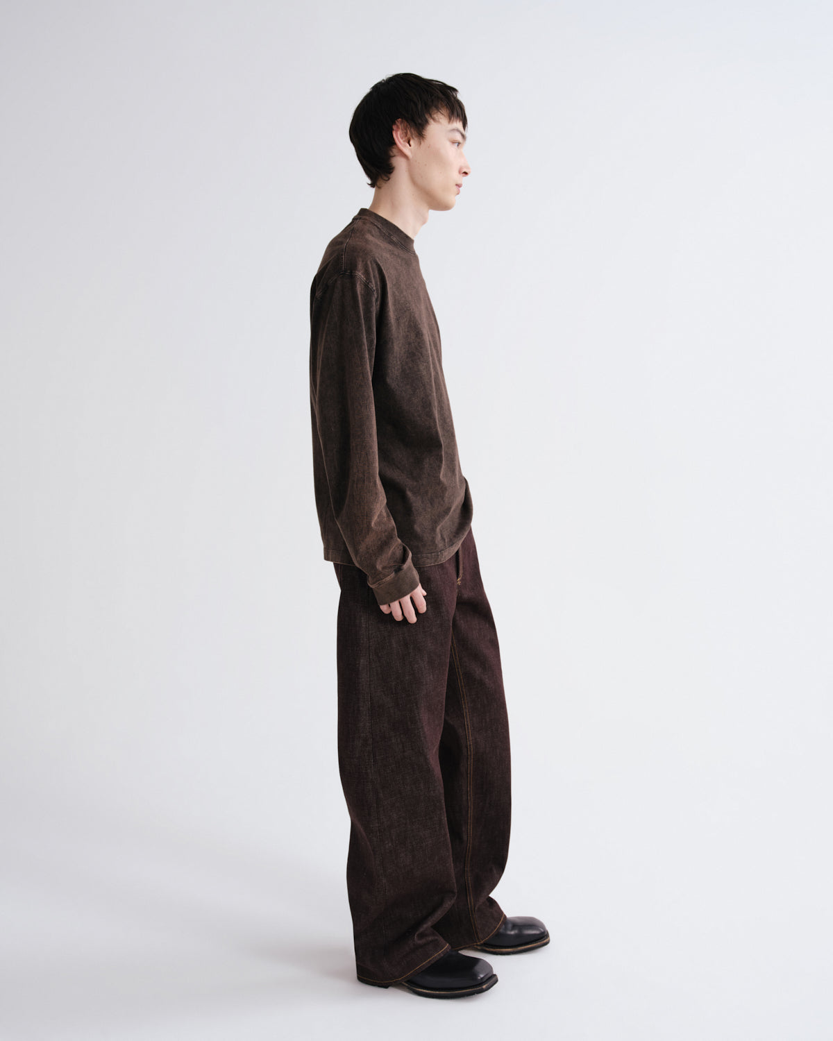 Person wearing a brown textured sweater and pants on a white background
