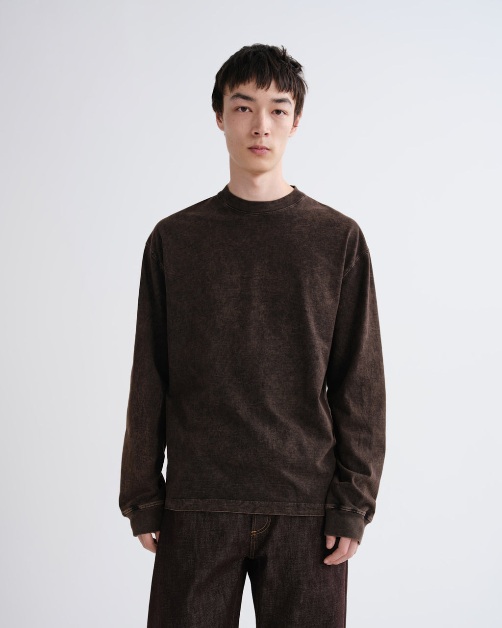 Person wearing a brown sweatshirt and pants on a white background