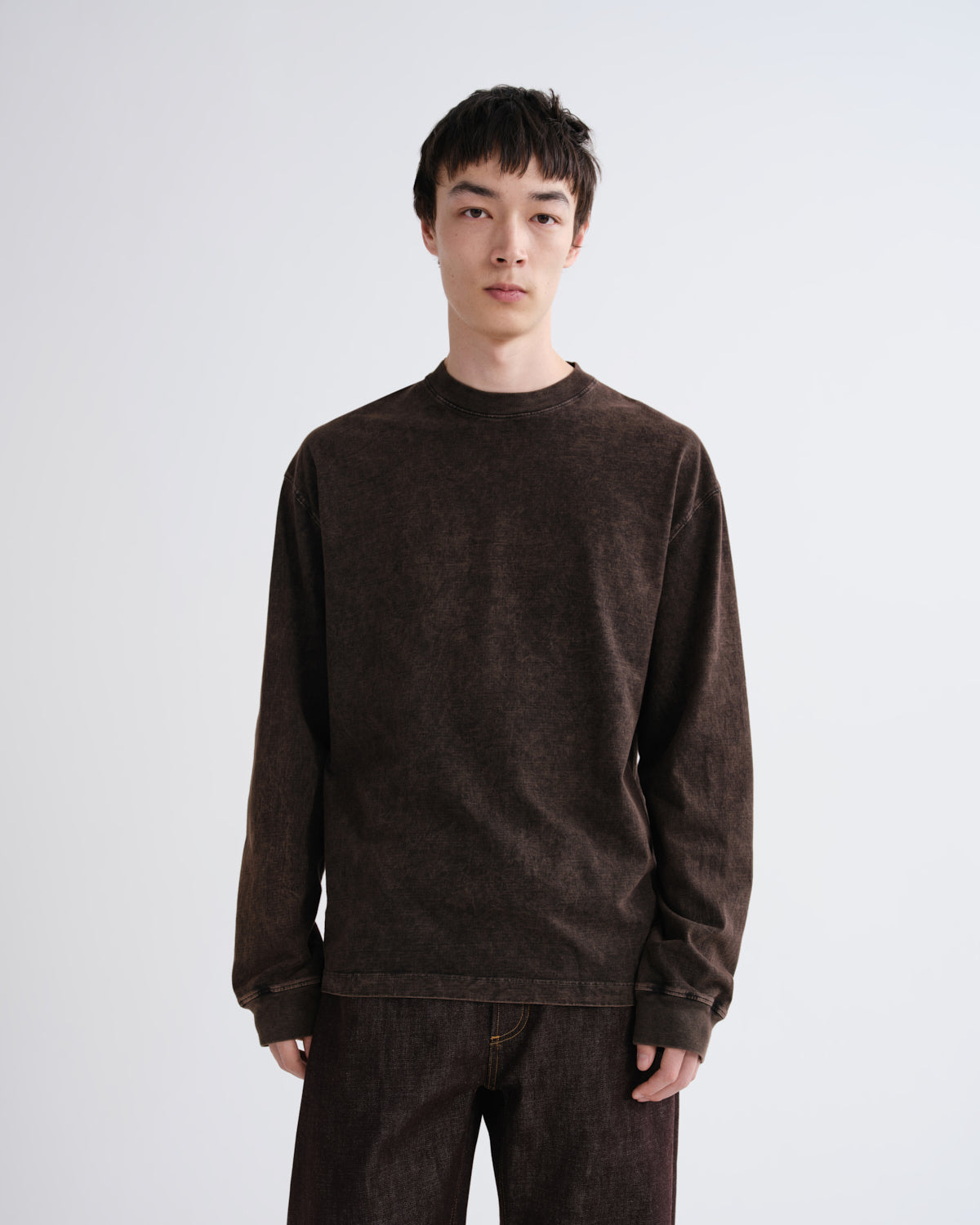 Person wearing a brown sweatshirt and pants on a white background