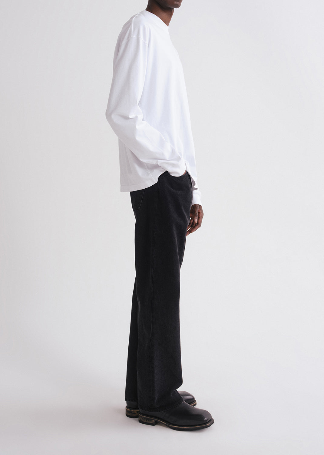 Person wearing a white shirt and black pants on a grey background