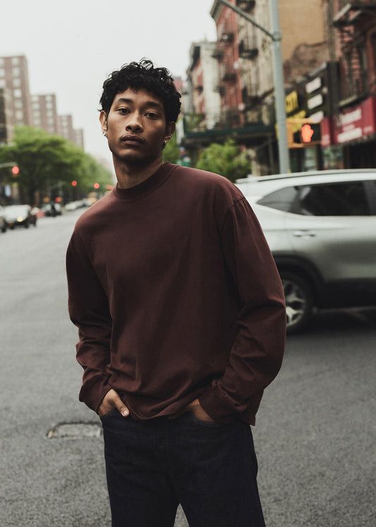Man standing on a city street wearing a brown sweater