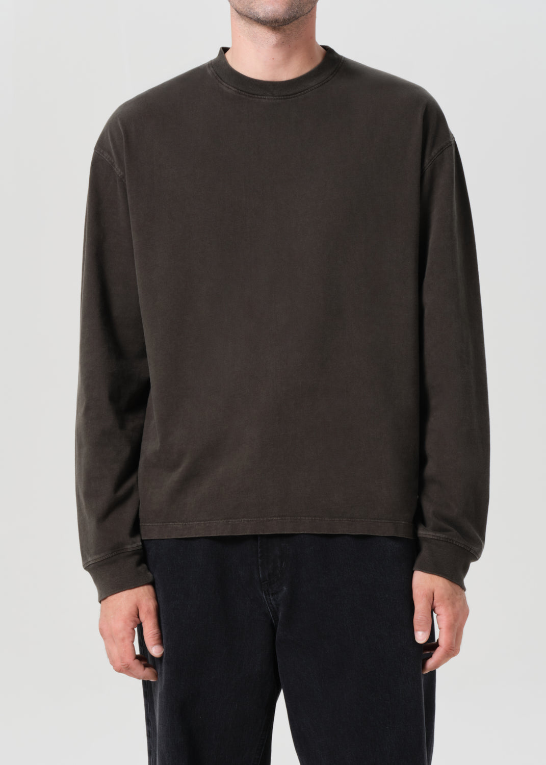 Person wearing a dark brown long-sleeve shirt against a plain background