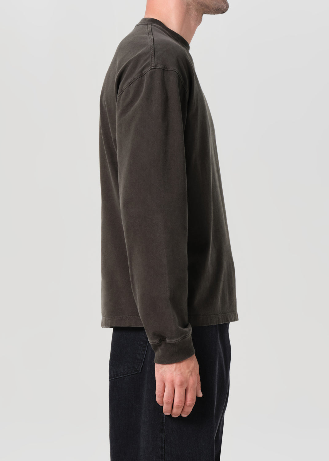 Person wearing a dark long-sleeve shirt on a plain background