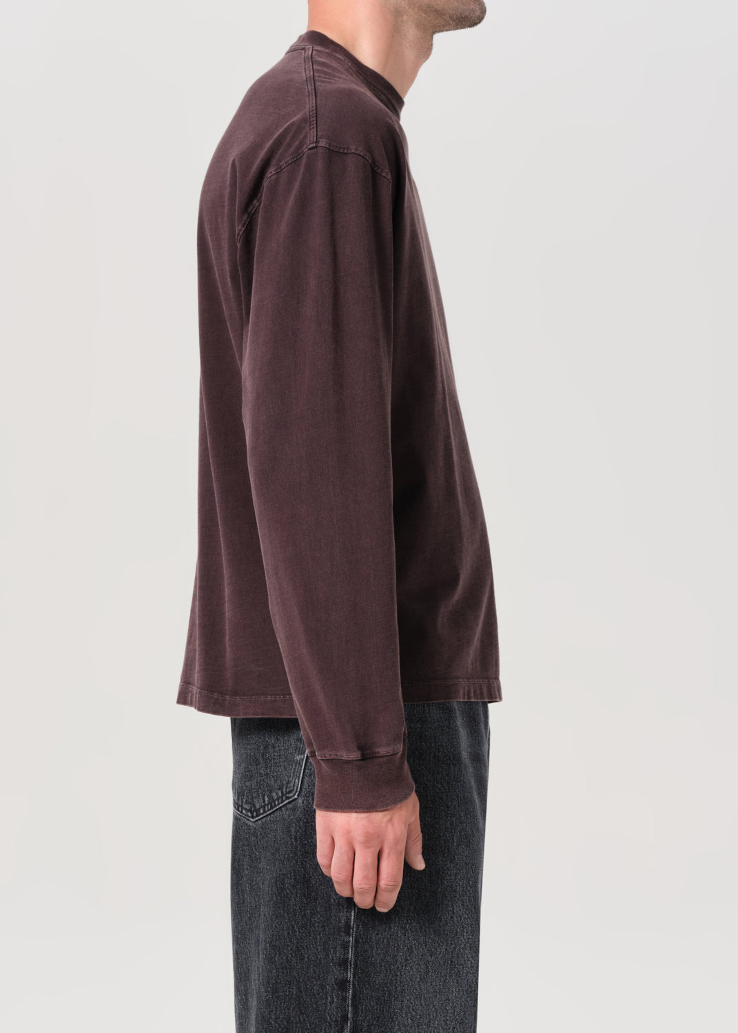 Person wearing a brown long-sleeve shirt on a light gray background