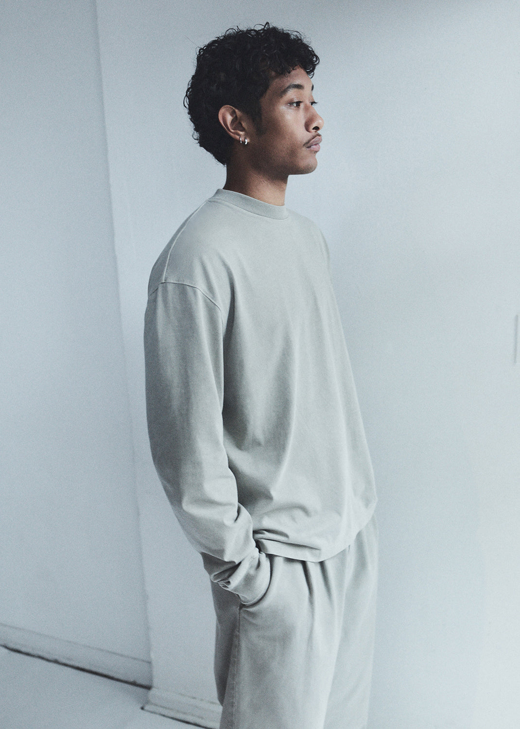 Person wearing a light gray outfit against a white background