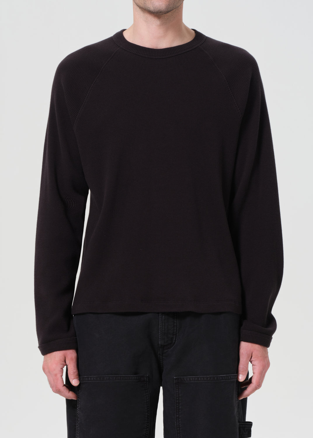 Black long-sleeve shirt worn by a person on a plain background