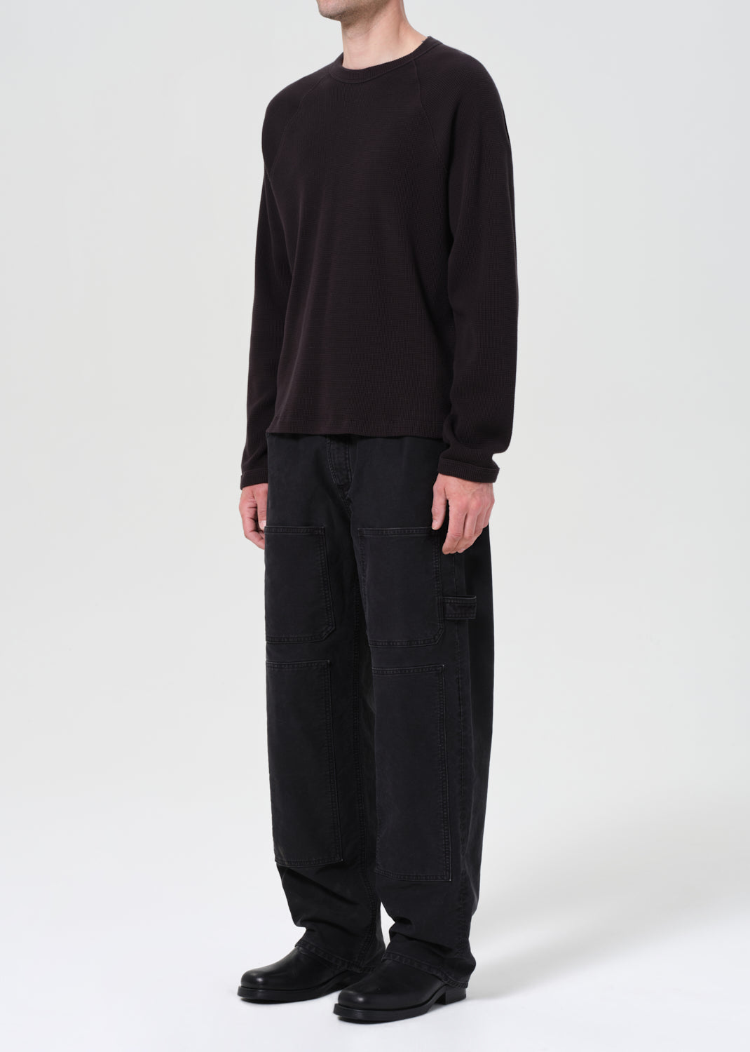 Person wearing a black long-sleeve shirt and black pants on a white background