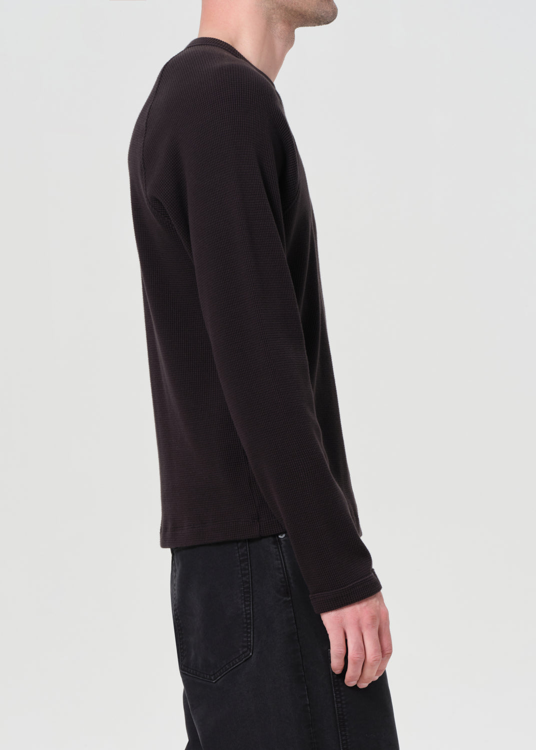 Person wearing a black long-sleeve shirt on a plain background